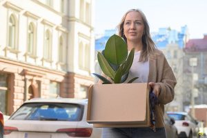 Nainen kantaa muuttolaatikko kaupungin kadulla